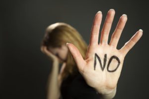 A woman with her hand up with "no" written on it