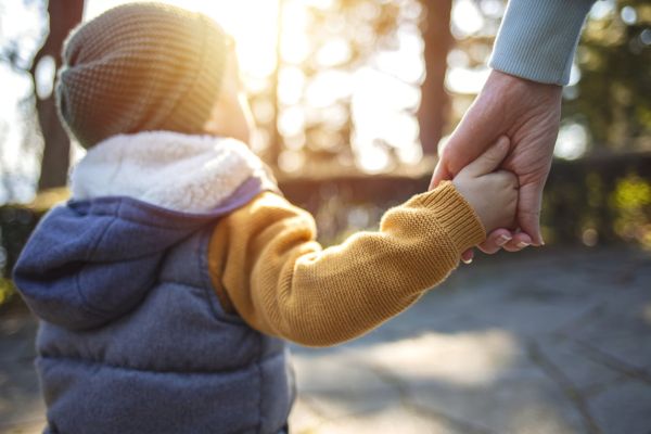 Close up of mother and a child hands at the sunset.